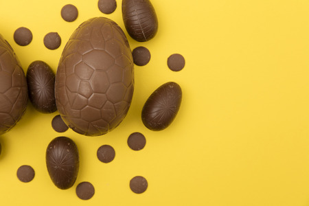 Chocolate easter eggs on a bright yellow background. Easter holiday conceptの写真素材