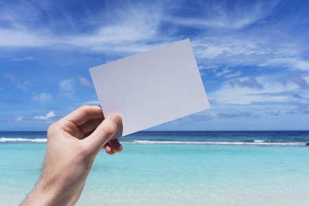 Hand holding blank white sign on a tropical summer beach の写真素材