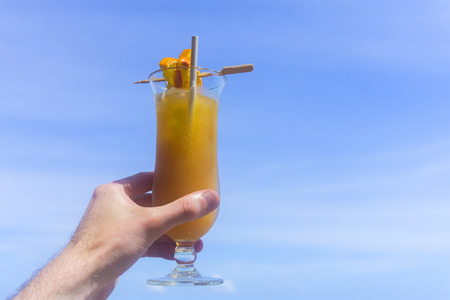 Tropical cocktail with orange against blue skyの写真素材