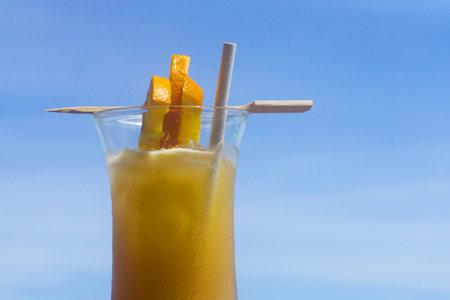 Tropical cocktail with orange against blue skyの写真素材