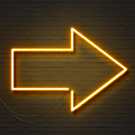 Yellow neon arrow sign on a brick wallの写真素材