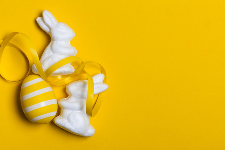 Easter bunny rabbit and eggs on a bright yellow background