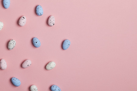 A collection of easter eggs on a pastel pink background