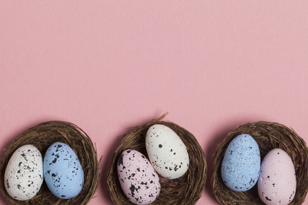 Easter eggs in a nest on a pastel pink backgroundの写真素材