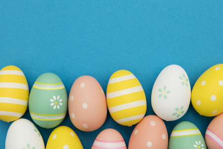 Easter holiday background. Pastel colored decorated easter eggs on a bright blue backgroundの写真素材