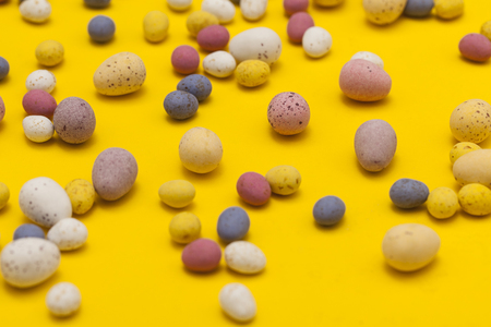Easter egg candy chocolates on a bright yellow springtime background