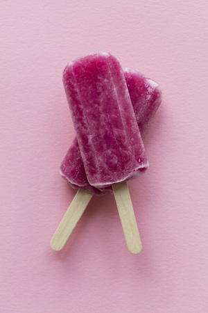 Raspberry flavour summertime ice lollies on a pink backgroundの写真素材
