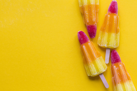 Rocket shaped summer ice lolly on a bright yellow backgroundの写真素材