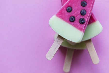 Watermelon shaped summer ice lolly on a pastel pink background