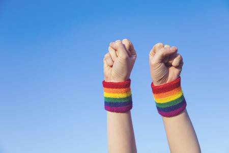 Gay pride concept. Hand making a fist sign with gay pride LGBT rainbow flag wristbandの写真素材