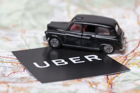 London, UK - MARCH 23rd 2017: A photograph of the Uber logo with a black London style taxi toy car. Uber is a popular taxi style transport service application, founded in 2009のeditorial素材