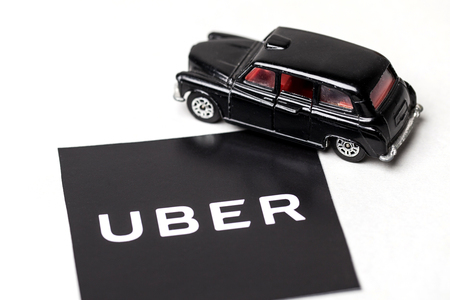 London, UK - MARCH 23rd 2017: A photograph of the Uber logo with a black London style taxi toy car. Uber is a popular taxi style transport service application, founded in 2009のeditorial素材