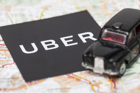London, UK - MARCH 23rd 2017: A photograph of the Uber logo with a black London style taxi toy car. Uber is a popular taxi style transport service application, founded in 2009のeditorial素材