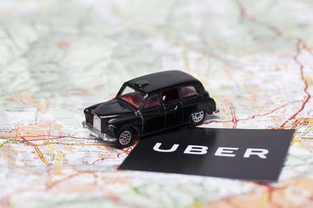 London, UK - MARCH 23rd 2017: A photograph of the Uber logo with a black London style taxi toy car. Uber is a popular taxi style transport service application, founded in 2009のeditorial素材