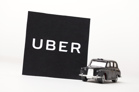 London, UK - MARCH 23rd 2017: A photograph of the Uber logo with a black London style taxi toy car. Uber is a popular taxi style transport service application, founded in 2009のeditorial素材