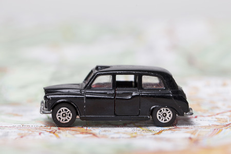 London, UK - MARCH 23rd 2017: A photograph of a black London style taxi toy car on a city road map