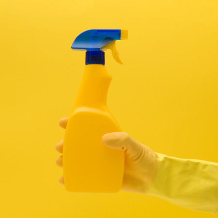 Hand in yellow rubber glove with cleaning productの写真素材