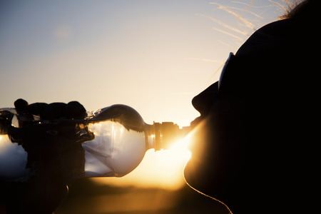 Silhouette of a woman drinking water at sunset