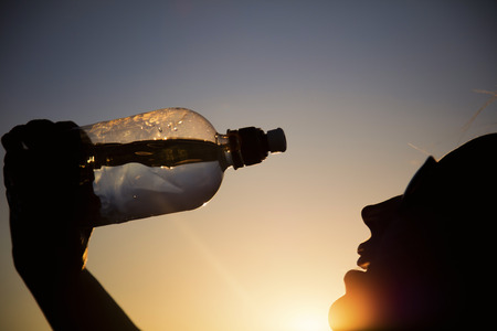 Silhouette of a woman drinking water at sunset