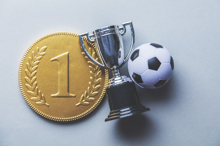 Gold first place winners medal and trophy with a soccer ball. Football success achievement conceptの写真素材