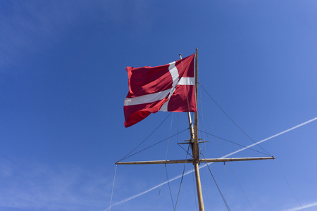Denmark flag on a ship mast waivng against a clear blue skyの写真素材