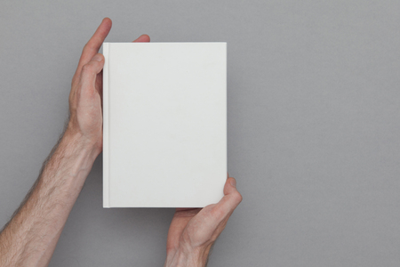 Male hand holding a closed book showing the book cover. Book Mock up template.の写真素材