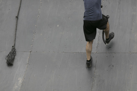 Adventure obstacle course race participant climbing a wall with a ropeの写真素材