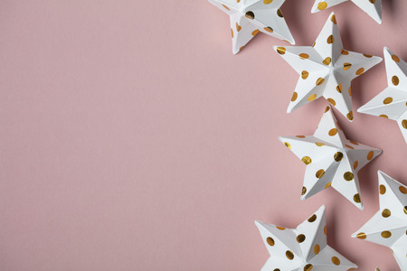 White and gold star decorations on a pastel pink. Seasonal festive backgroundの写真素材