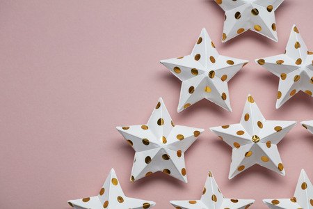 White and gold star decorations on a pastel pink. Seasonal festive backgroundの写真素材