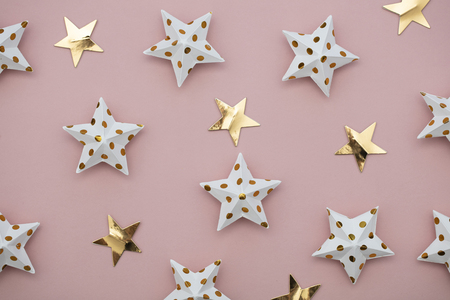 White and gold star decorations on a pastel pink. Seasonal festive backgroundの写真素材