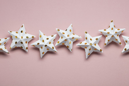 White and gold star decorations on a pastel pink. Seasonal festive backgroundの写真素材
