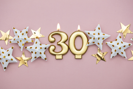 Number 30 gold candle and stars on a pastel pink backgroundの写真素材