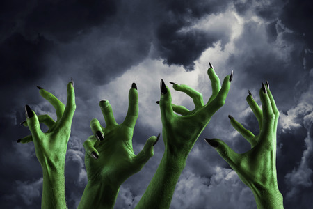 Halloween green monster hand with black fingernails against a dark skyの写真素材