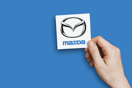 LONDON, UK - October 26th 2018: Hand holding a Mazda icon. Mazda is an automobile manufacturer.のeditorial素材