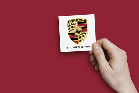 LONDON, UK - October 26th 2018: Hand holding a Porsche icon. Porsche is an automobile manufacturer.のeditorial素材