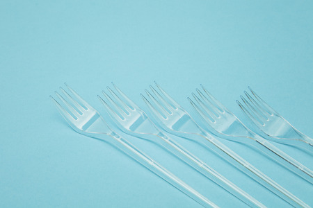 Plastic cutlery forks arranged on a blue background. Plastic waste problemの写真素材