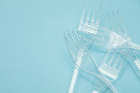 Plastic cutlery forks arranged on a blue background. Plastic waste problem