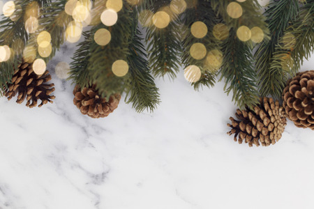 Christmas fir tree branches and bokeh blurred fairy lights on a marble backgroundの写真素材