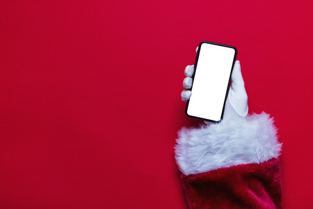 Santa Claus Christmas hand holding a phone against a red backgroundの写真素材