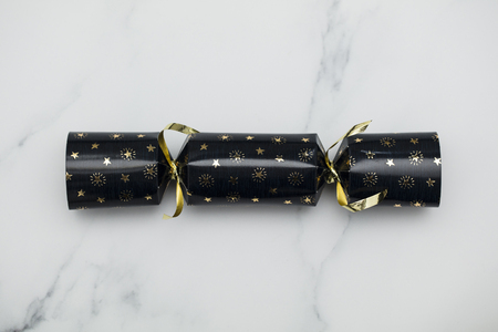Christmas crackers. luxury gold and black festive crackers on a marble backgroundの写真素材