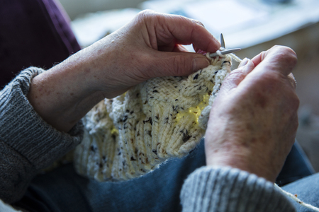 Close up of an older womens hands knitting a jumperの写真素材