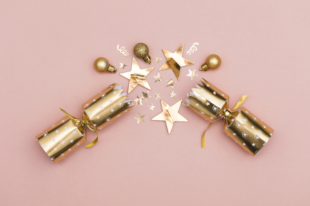 Christmas crackers. luxury gold festive cracker on a pastel pink backgroundの写真素材
