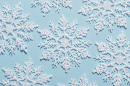 White glitter snowflake composition on a pastel blue background