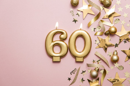 Number 60 gold celebration candle on star and glitter background