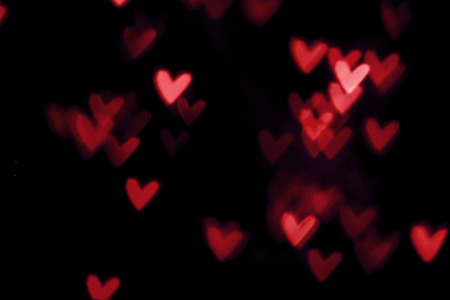 Red heart valentine bokeh lights against a black background