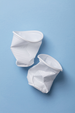 Single use white plastic cups on a blue backgroundの写真素材