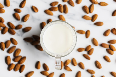 Almond milk in a glass surrounded by organic almondsの写真素材