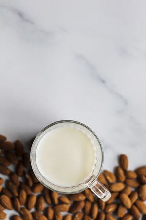 Almond milk in a glass surrounded by organic almondsの写真素材