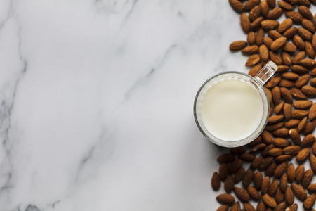Almond milk in a glass surrounded by organic almondsの写真素材