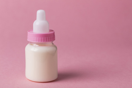 Baby bottle full of milk on a pink backgroundの写真素材